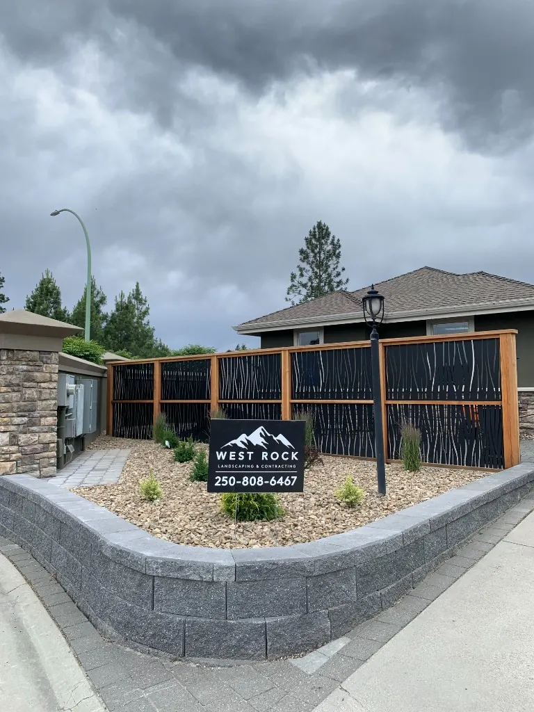 Residential landscaping with block retaining wall, gravel bed, and decorative privacy fence